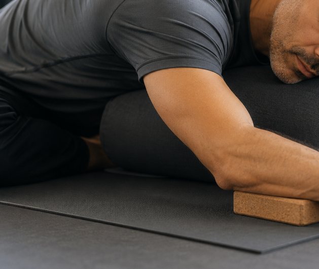 Postura de Yin Yoga apoiada em bloco de cortiça, num ginásio OSTEOENERGY